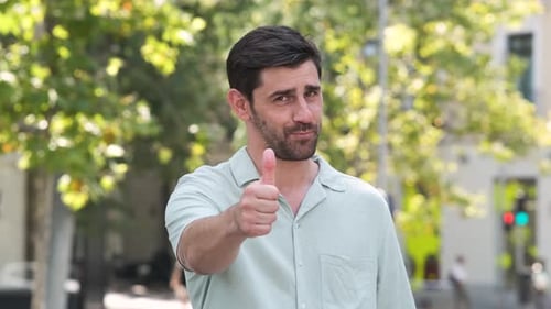 Happy Man in Casual Shirt Showing Thumbs Up at City Park During Sunny Day