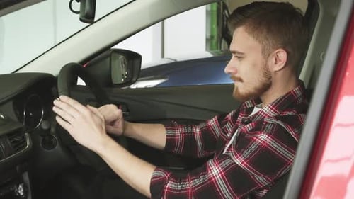 Confident Young Man Exploring the Interior of a Sleek New Car at the Dealership