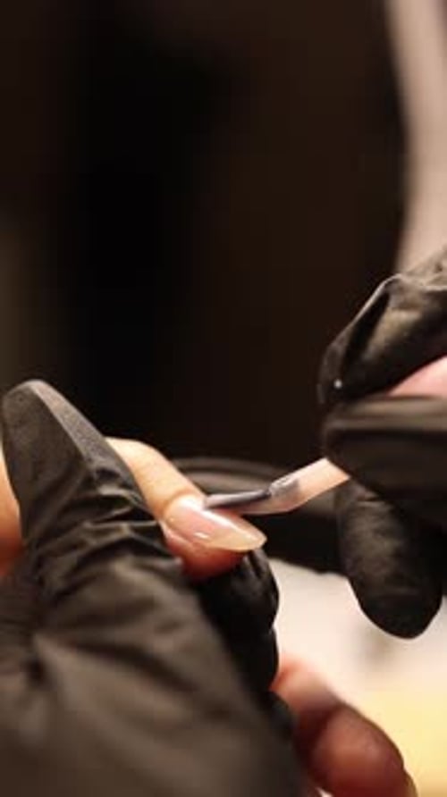 Applying Top Coat to Manicured Nail in Beauty Salon
