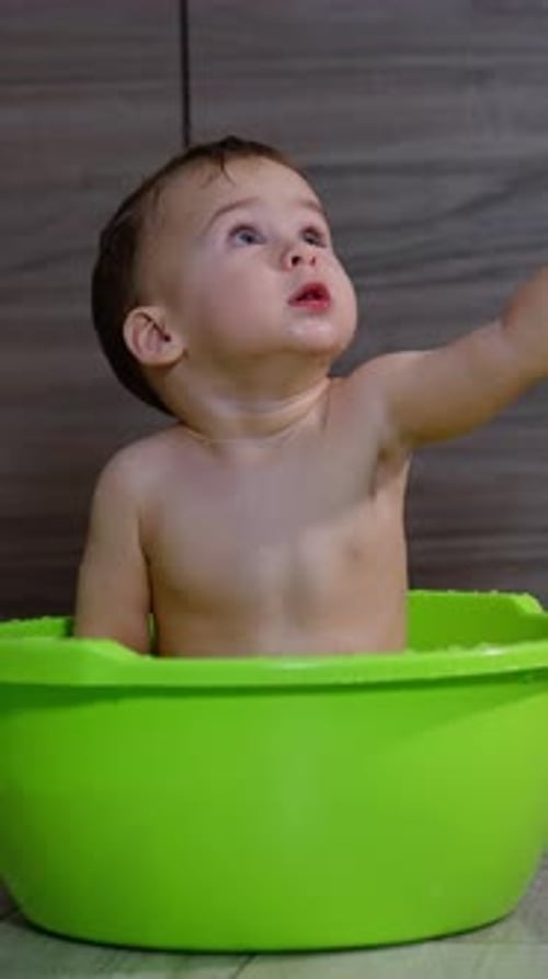 Adorable Infant Taking a Bath in Green Basin