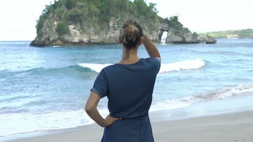 Junge Frau bewundert das Meer, das am Strand auf einer exotischen Insel der 30er Jahre steht
