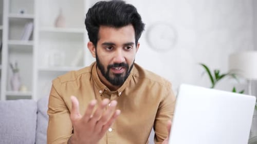 Close up. Young businessman talking on video call using laptop while sitting on sofa in living room