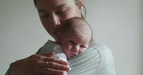 Authentic shot of young neo mother is keeping in arms and caressing her newborn baby in a nursery
