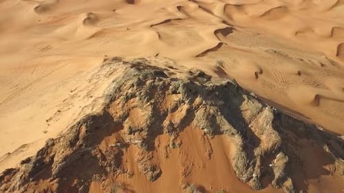 Majestic Aerial View of a Desert Rock Formation Surrounded by Sand Dunes