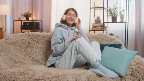 Woman Listens to Music on Couch with Headphones
