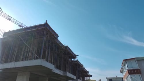 Vídeo aéreo: vista aérea del sitio de construcción con grúa cargando materiales y manipulando trabajadores