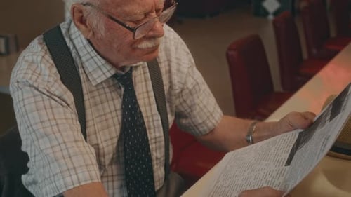 Senior Man Reads Newspaper in Retro Diner