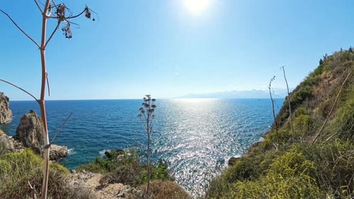 Scenic view of the Ocean with Mountains in the distance, the Sun shining brightly over the water.