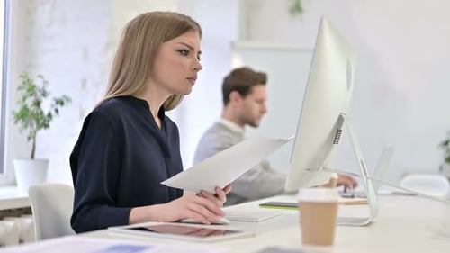 Woman Reviews Documents at Office Desk