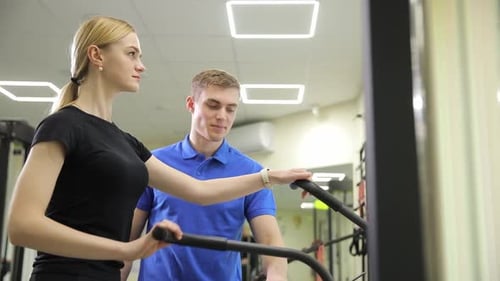 A Dedicated Personal Trainer is Actively Guiding Their Client Throughout the Gym Session