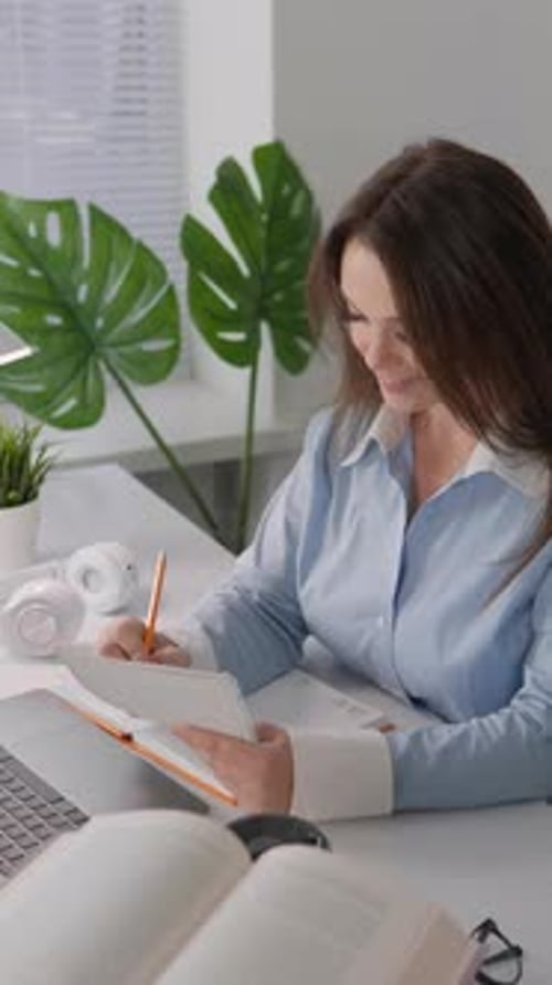 In This Vertical Video a Young Woman Working on a Laptop at Her Workplace at Home She is Seriously