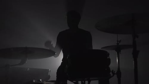 Silhouette eines männlichen Schlagzeugers, der im Dunkeln Schlagzeug spielt