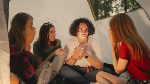 Friends Telling Scary Story Inside Tent While Camping