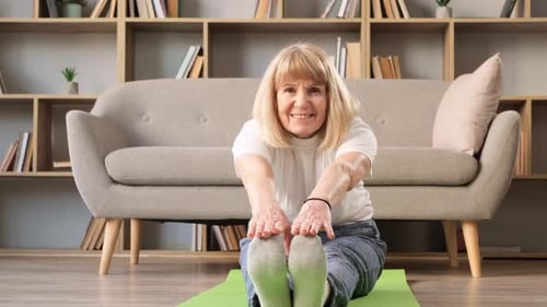 Senior Woman Stretching on Yoga Mat at Home