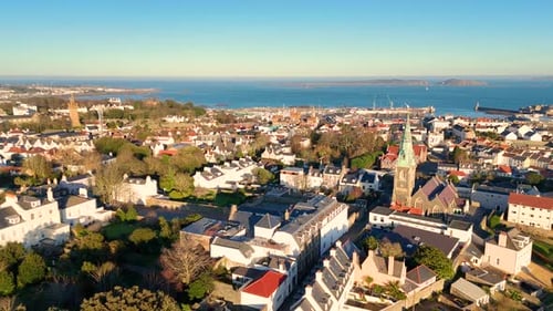High panning drone footage of the roof tops of St Peter Port Guernsey in the golden hour with views