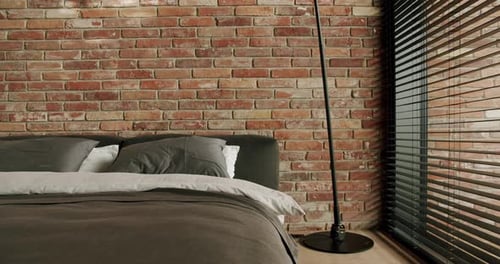 Bed with pillows and blanket at modern hotel room with loft interior