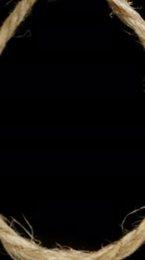 Vertical video. Sliding Through A Noose On A Rope, Isolated On A Black Background, Concept Of Being
