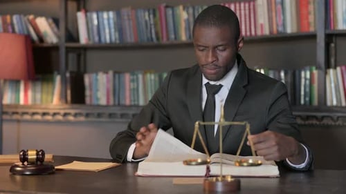 African American Lawyer Reading Law Book in Office