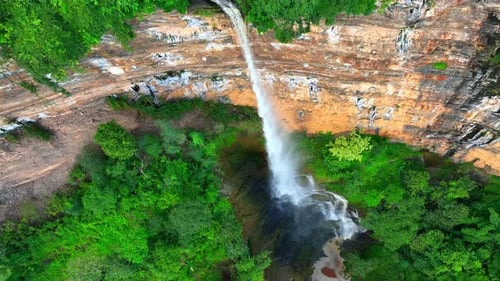 Aerial view: Majestic waterfall cascades from cliff.