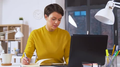 Hispanic businesswoman working with laptop and notebook in modern office