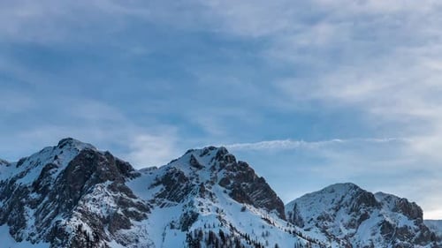 Panning on snow covered mountain peaks and the movement of clouds. Time Lapse.
