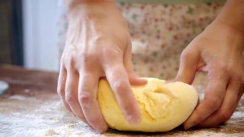 Hands Kneading Dough on Flour-Dusted Wooden Surface