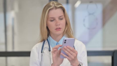 Young Blonde Doctor Using Mobile Phone in Hospital