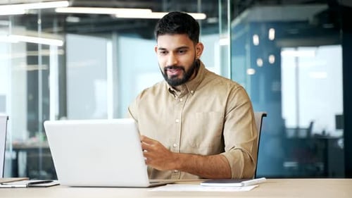 Businessman sitting at office desk having video call on laptop. Male professional talking