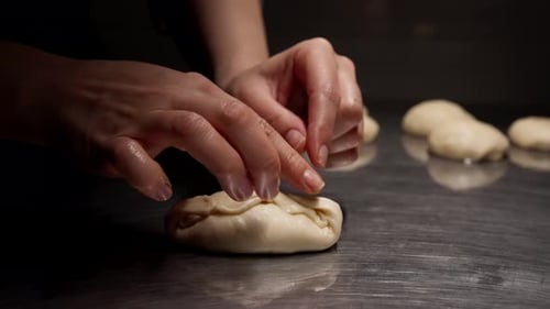 Baker Shapes Dough into Dumpling on Metal Counter
