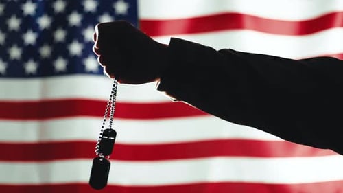 Silhouette Holds Dog Tags Before American Flag