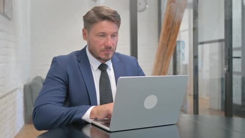 Professional Man Working on Laptop in Bright Office