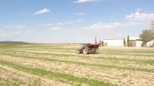 Tractor Spreading Fertilizer Across Rural Field