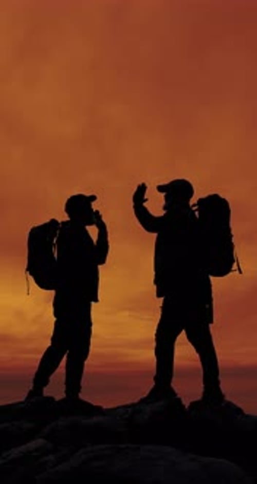 People, silhouette and high five for hiking at sunset on mountain, friends and space on adventure