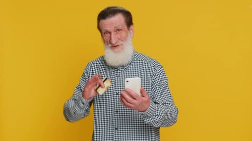 Happy Senior Man Grandfather Using Credit Bank Card and Smartphone While Transferring Spending Money
