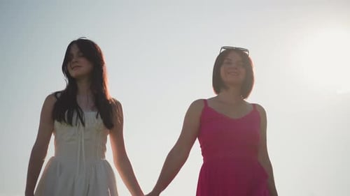 Asian Women Enjoy Peaceful Nature Two Women Hold Hands in Sunlit Meadow Scene Asian Women in Flowing