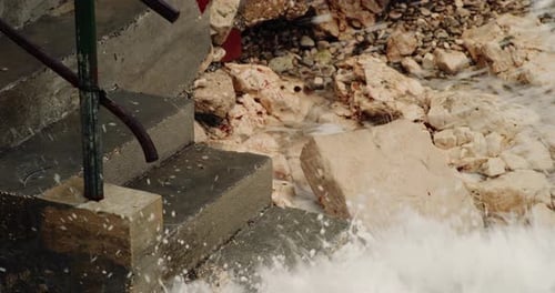 Ocean waves crash on exposed concrete slabs eroded away from water exposure