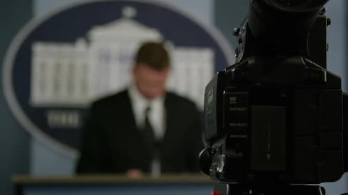 Video Camera Focused on Blurred Man at Podium