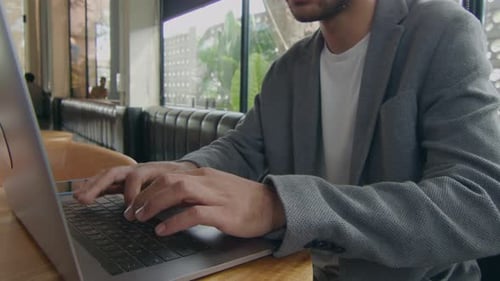 Young Adult Typing on Laptop in Modern Office