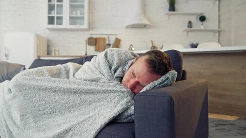 Homme malade sous une couverture chaude sur un canapé confortable à la maison. Pandémie. Concept de quarantaine.