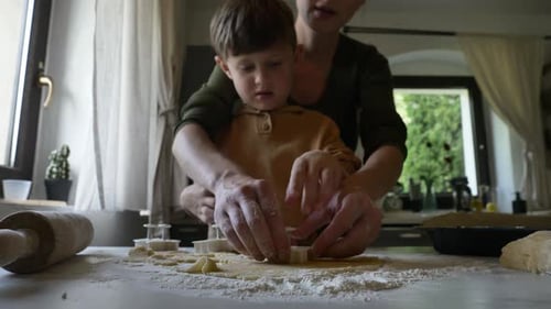 Mother and son making gingerbread cookies at kitchen at home, Poland