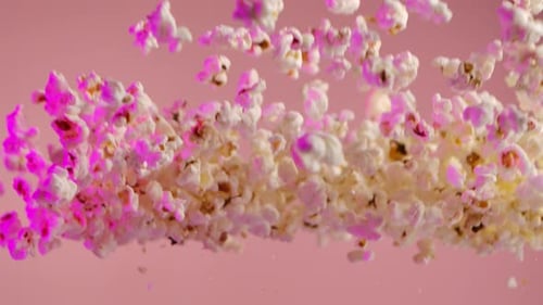 Foto em super câmera lenta de pipoca em fundo rosa após ser explodida