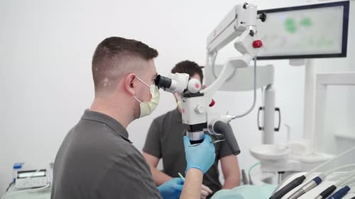 Male Dentist Working with Dental Microscope in Modern Stomatology Clinic Doctor Using Microscope for