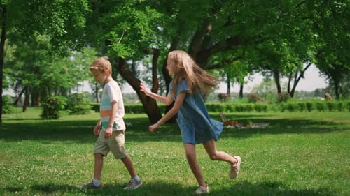 Cheerful sister catches little brother during active family picnic game in park
