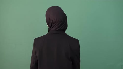 Woman Points at Camera Against Green Background