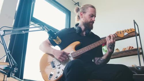 Young Man Playing Electric Guitar in Home Studio