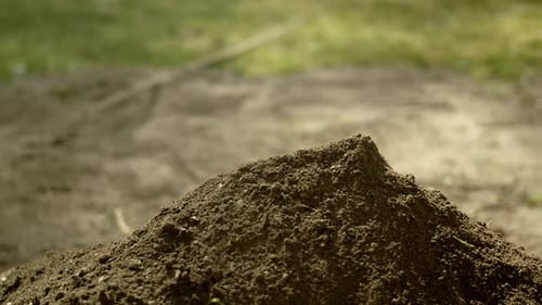 Shovel scoops dirt from dig onto growing pile, slow motion