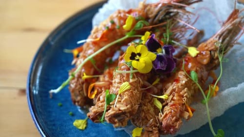 Crispy Almondcrusted Prawns Drizzled with Sweet Chili Sauce Garnished with Edible Flowers and