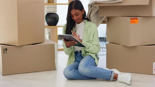 Woman Using Tablet Surrounded by Moving Boxes