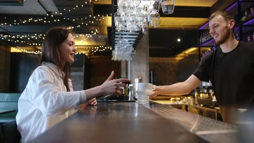 Woman Receives Coffee From Bartender at Bar