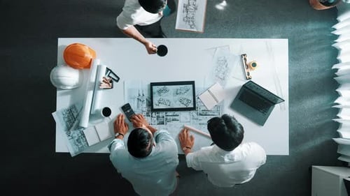 Top view of manager looking at plan while designer hold blueprint. Alimentation.